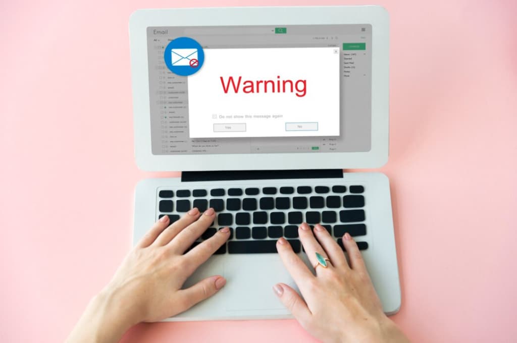 Hands typing on a laptop with an email warning message pop-up on the screen